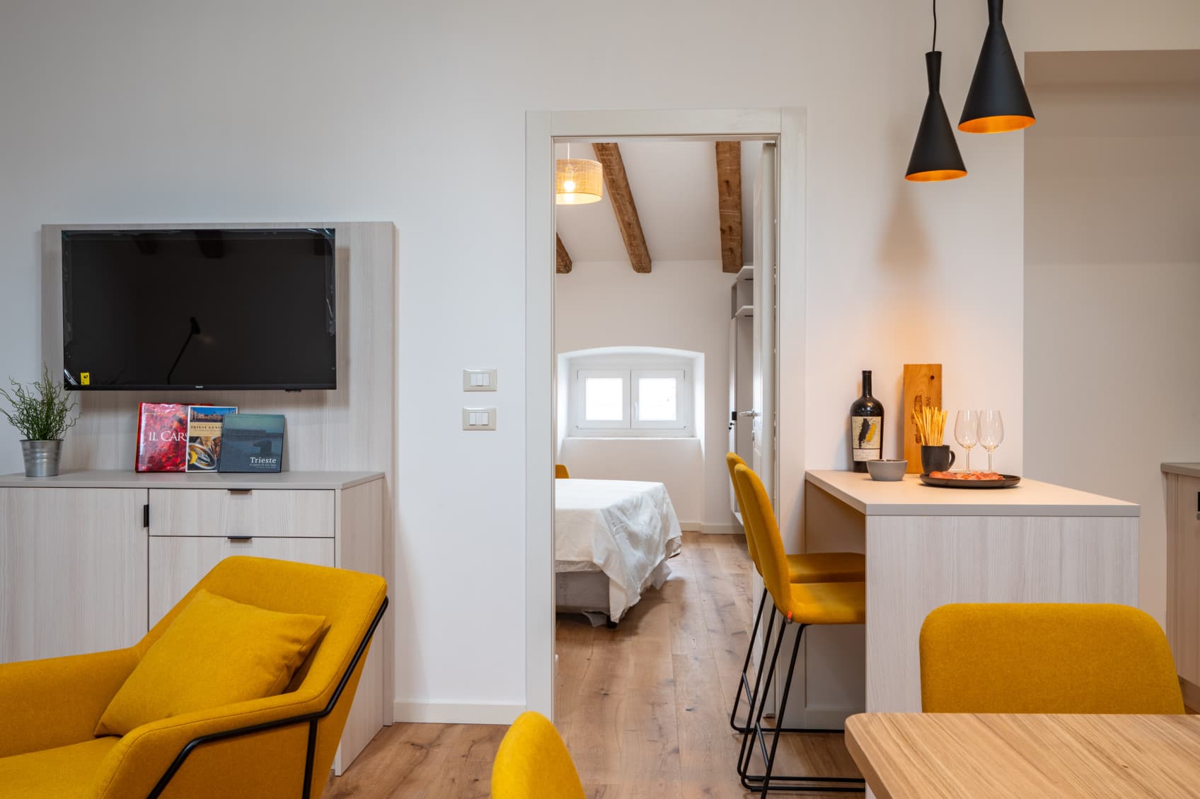 Bilder zeigen das gemütliche Apartment mit einer voll ausgestatteten Küche und einem Wohnzimmer. Der Blick geht auf das angrenzende Schlafzimmer.